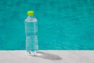 Water bottle placed beside the swimming pool.